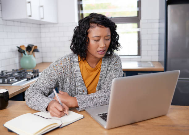 istock A young multi-ethnic woman works from home in the kitchen taking notes 1418240857