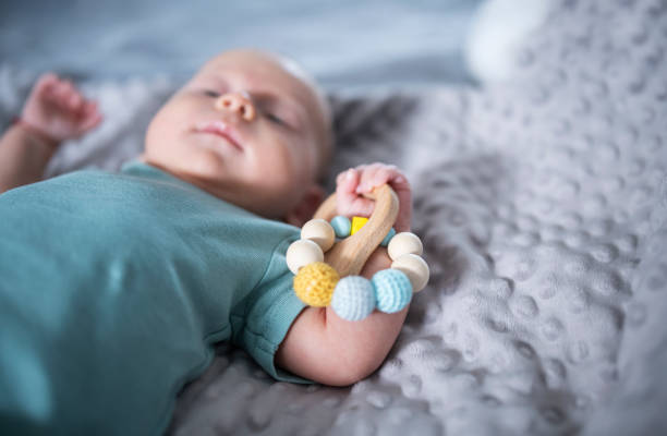 Baby boy holding a chewing teething toy.