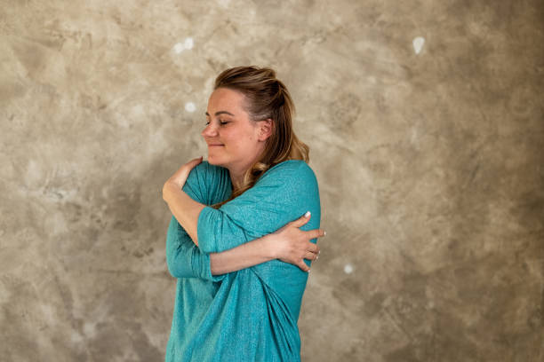 istock Woman embracing herself against colored background 1418249128