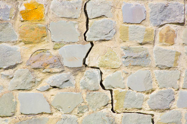 Old cracked and damaged stone wall cause due to subsidence of foundations structural failures