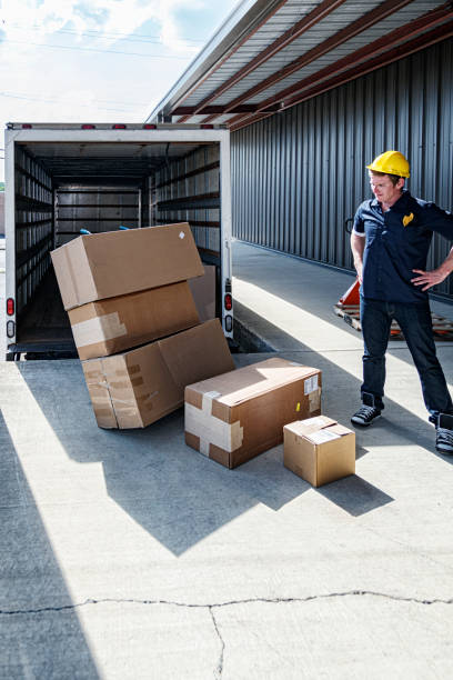 istock Tired Loading Dock Worker Staring Down at Damaged Cardboard Cartons 1418256586