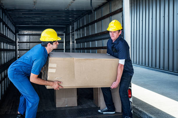 Two Loading Dock Workers Carrying Heavy Cardboard Box stock photo