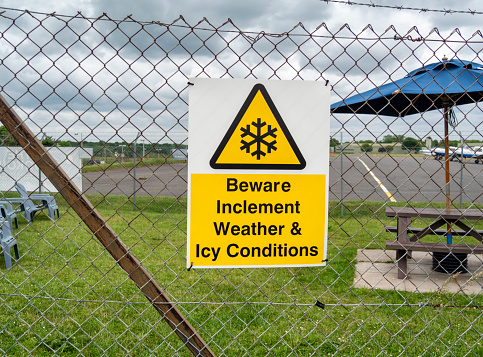 A sign on a fence surrounding a small regional airport in Kent, England, warning of “Inclement Weather and Icy Conditions”.