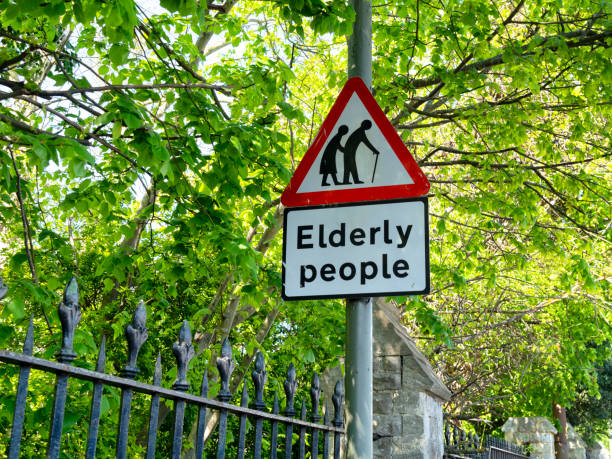 Outside an urban cemetery fence, a sign warning of ‘Elderly People’. (A care home is nearby.)