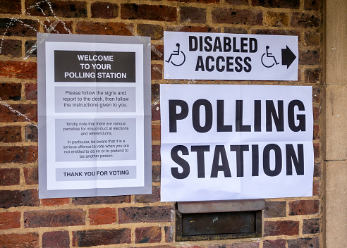 Outside an English suburban polling station, a collection of notices giving instructions on accessing and using the facility.