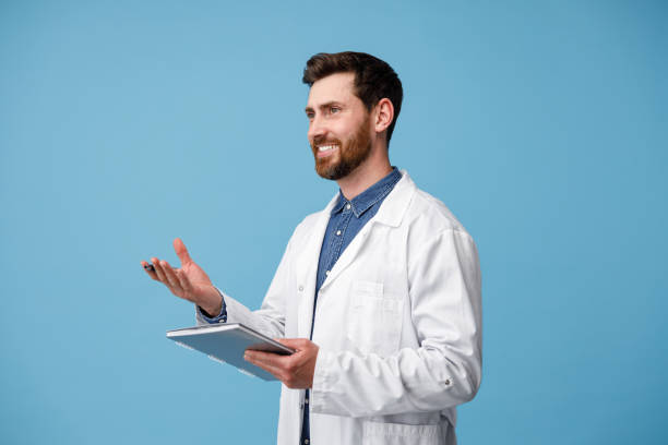 istock Doctor consults patient holding tablet in hands standing over blue studio background 1418259331