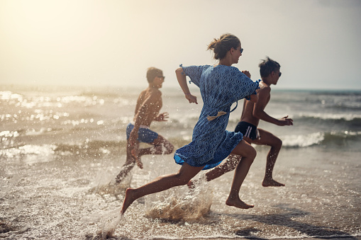 Three teenagers running in the sea. Summer vacations day in Alicante, Spain.\nCanon R5
