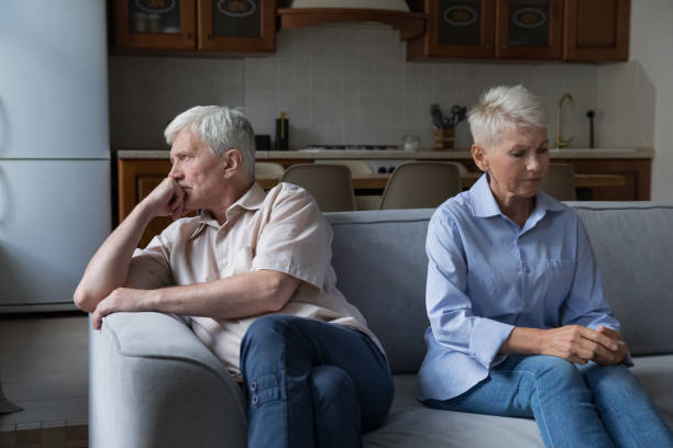 istock Serious older couple in quarrels sit on couch separately 1418260616