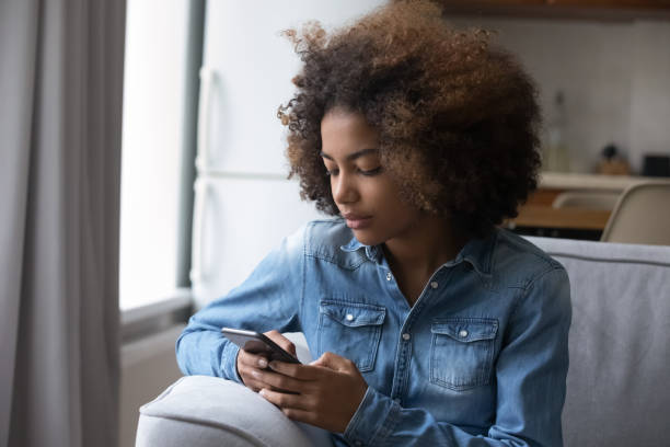 istock African teenage girl read message, send sms using smartphone 1418261647