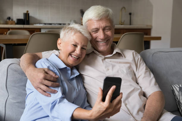 istock Older couple use smartphone make videocall seated on sofa 1418262253