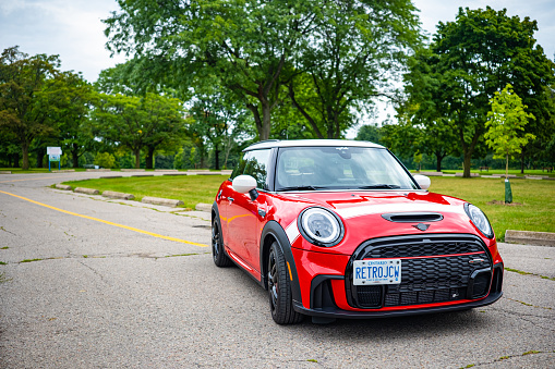 Toronto, Ontario, Canada- August 26, 2022. Chili red colour MINI COOPER on the road in public park in Toronto East side, Canada. This is the third generation model F56 JCW, since BMW took over iconic brand of MINI. MINI featured in the photo is John Cooper Works model, the most powerful 2 door version. For the first time, this compact car features engine build and designed by BMW, and packs even more power and torque than previous models since 2002 to present. Original design clues and themes are still present on this brand new model. Mini has been around since 1959 and has been owned and issued by various car manufacturers.
