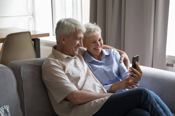 istock Happy mature couple sit on sofa using modern smartphone 1418262724