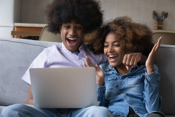 istock Happy African couple read e-mail on laptop celebrate auction win 1418262738