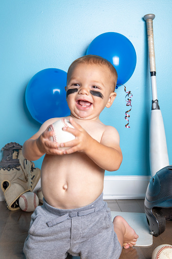 A one year old baby boy celebrating his birthday with a baseball theme.