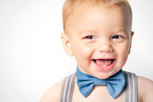 A one year old baby boy in a bow tie smiling.