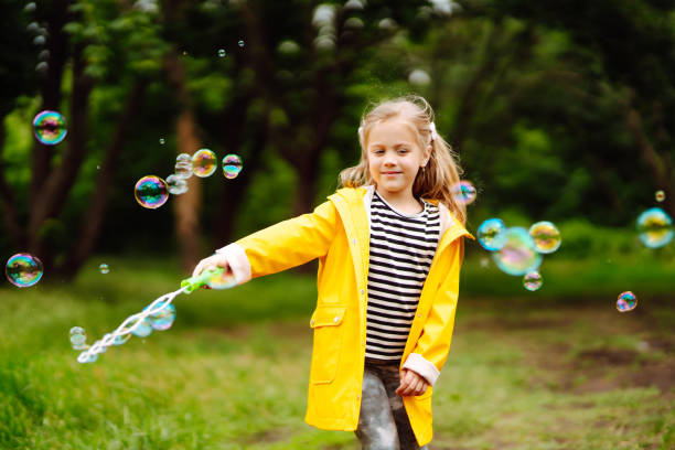istock Little girl blowing soap bubbles outdoors in the park. 1418264531