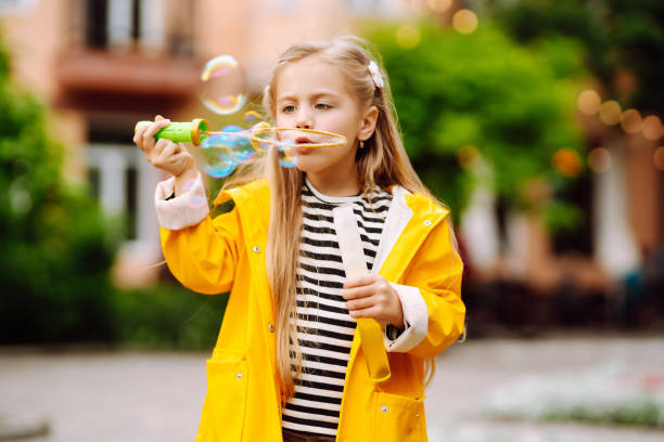 istock Little girl blowing soap bubbles outdoors in the park. 1418264559