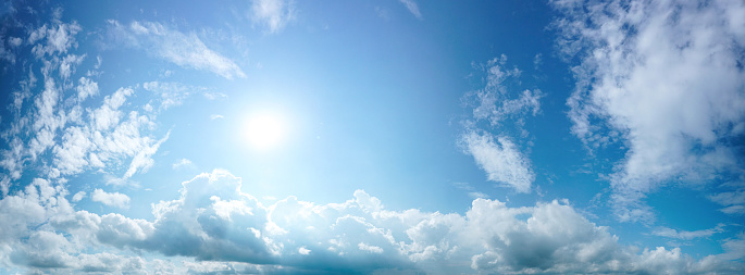 Beautiful bright blue sky panorama with white clouds and bright sun.