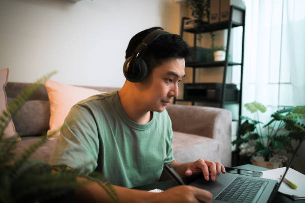 istock Adult Student man wearing headphone while e-learning on laptop 1418268586