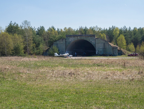 Czech Republic, Ralsko, April 26, 2019: former Soviet army concrete shelter, serving as hangar on airport at former military training rang in the area of Ralsko. grassy and forest, springtime, blue sky