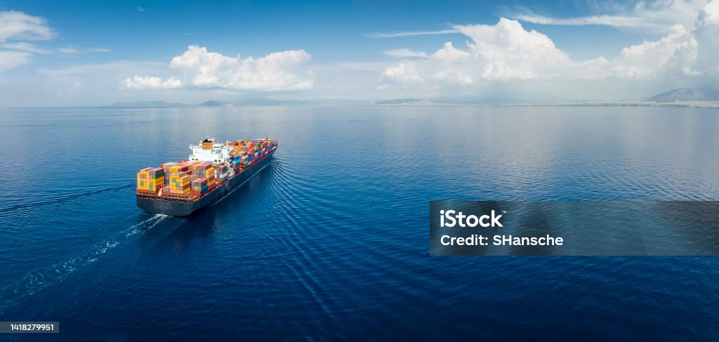 Panoramic aerial view of a industrial cargo container ship Panoramic aerial view of a industrial cargo container ship traveling over calm, open sea with copy space Container Ship Stock Photo