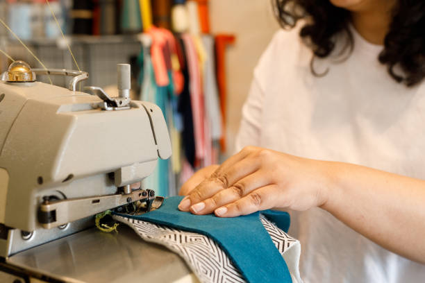 istock Human hand sewing two pieces of fabric together 1418281740