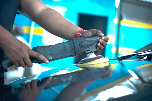 Asian man uses car polishing tools to maintain car's paintwork
