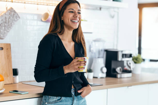 istock Beautiful young woman drinking coffee while standing in the kitchen at morning 1418290540