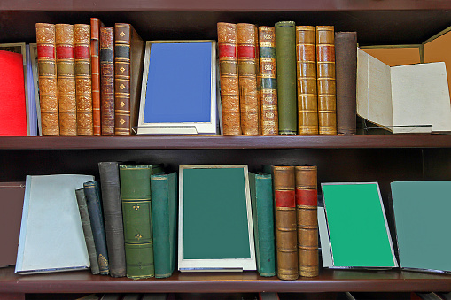 Stack of old vintage books with colorful hard covers on wooden shelves