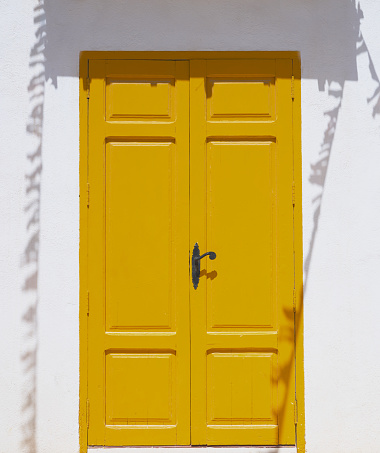 detail of a yellow door in the shadows on a whitewashed wall