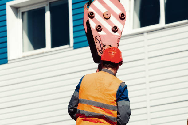 slinger de capacete e colete prende carga na rua entre casas para guindaste. - slinger - fotografias e filmes do acervo