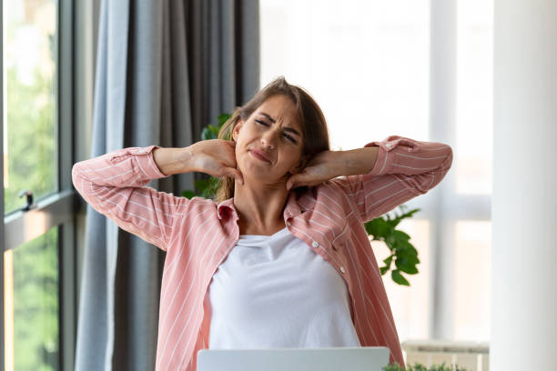 istock Feeling exhausted. Frustrated woman looking exhausted and massaging her neck while sitting at her working place 1418357082