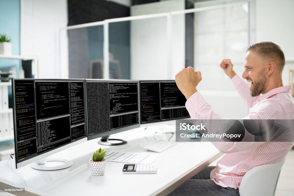Excited Programmer Using Multiple Computer Screens Stock Photo ...