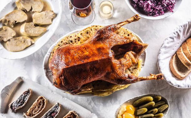 Roast goose with side dishes, red cabbage, roast, strudel, potato dumplings, pickles, bread and red wine. Traditional holiday food. Top view. stock photo