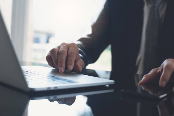 istock Businessman in black suit working on laptop computer and using mobile smart phone at modern office 1418363396