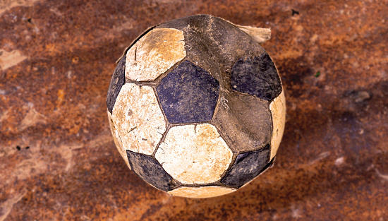 An old, unusable football thrown on a rusted metal plate, trimmed to tone the illustrations.