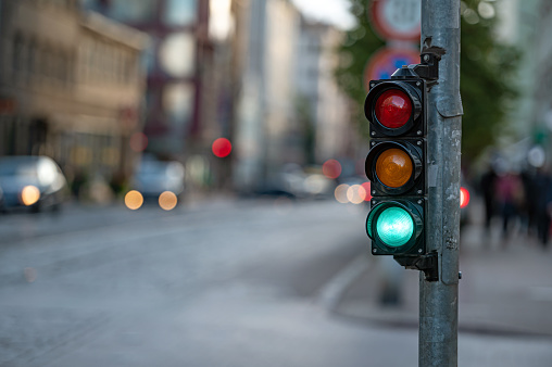 blurred view of city traffic with traffic lights, in the foreground a semaphore with a green light