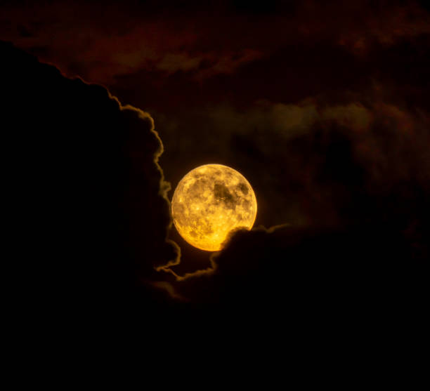 istock Red full moon rising from the clouds in silhouette. 1418372358