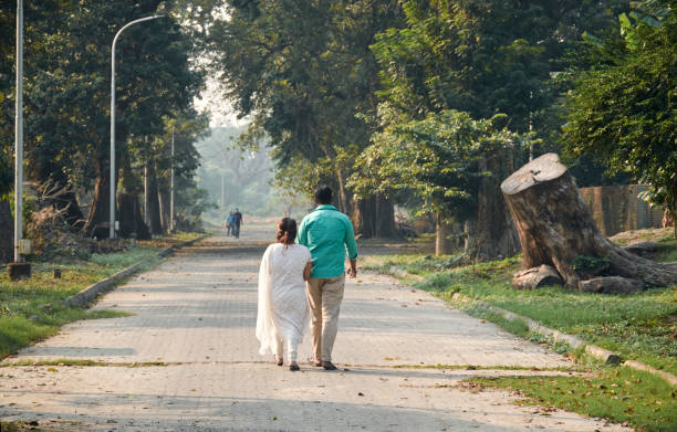 West Bengal, 11/27/2021 : a young couple walking together through garden pathway inside Acharya Jagadish Chandra Bose Indian Botanic Garden, a popular spot for nature lovers and young generation people.