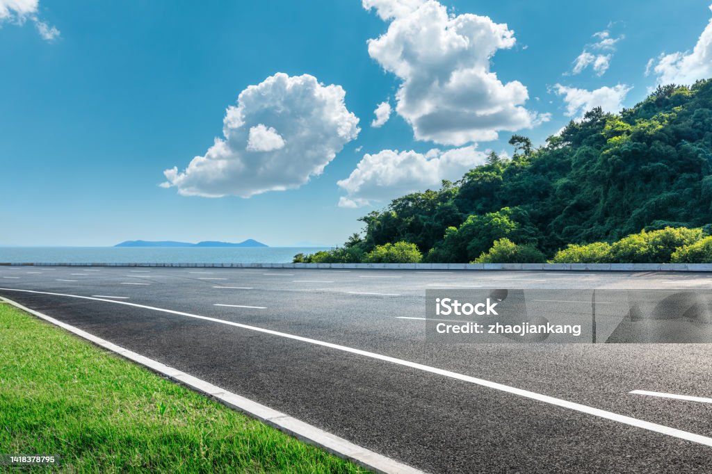 Asphalt and forest by the sea Asphalt and green mountains by the sea Road Stock Photo