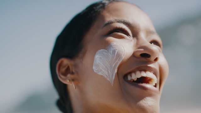Woman with sunscreen on face to protect skin at beach in summer, laughing on vacation and caring for skincare with cream outside in nature. Closeup portrait of face of a happy person with lotion