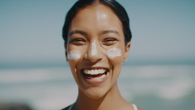 Beach, summer and holiday, a happy woman with sunscreen for protection and skincare in the sun. Fun at a dream sea vacation, a tourist in sand, waves and blue sky. Cheerful girl enjoying the sunshine