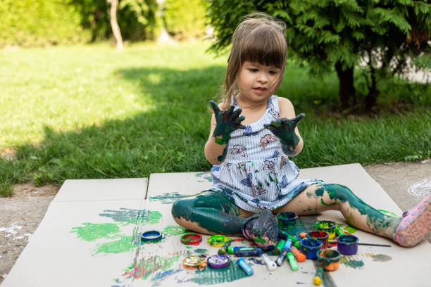 istock The child is looking at her hands. She is playing with watercolors. 1418382372