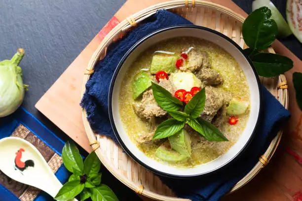 Photo of Asian Food concept Authentic Thai Green Curry beef and thai green eggplant on wooden board with copy space