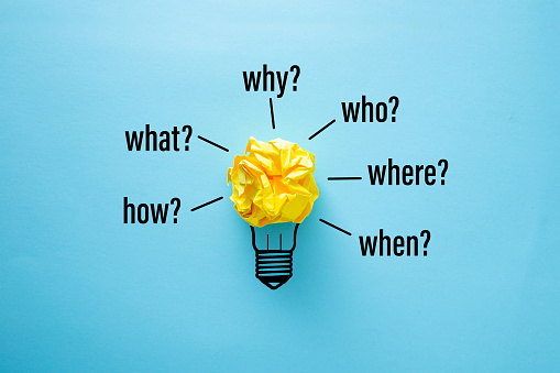 Yellow crumpled paper on blue background with words when, why, what, who, where and how.