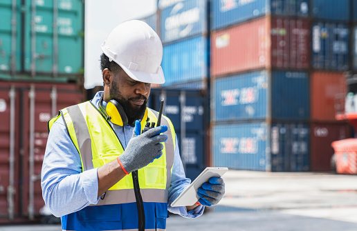 Portrait of Bearded man loading worker in reflection vest while standing in front of a shipping yard