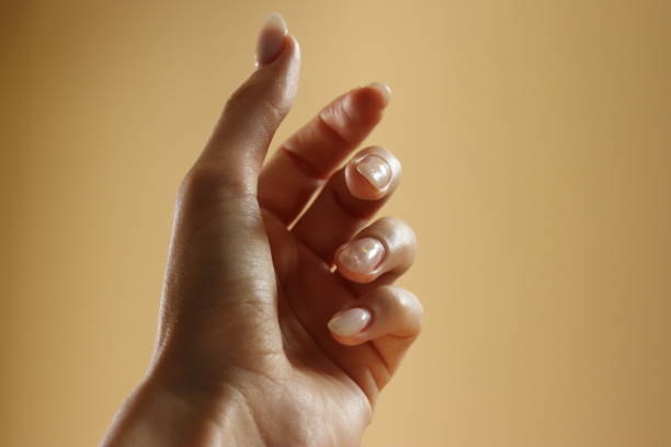 istock Female hand on yellow background with long nails 1418388535