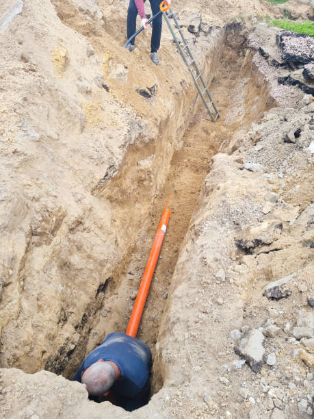 istock Man Digging Trench to Replace Sewer Line Pipes and Lawn Sprinkle 1418393358