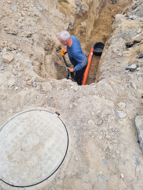 istock Man worker holding pipe, providing sewer cleaning service outdoor. Sewage pumping machine is unclogging blocked manhole 1418393365