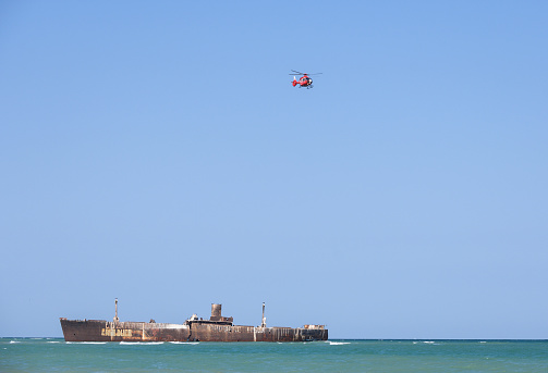Helicopter in flight and the wreck of a ship. Romania, Costinesti. August, 11, 2022